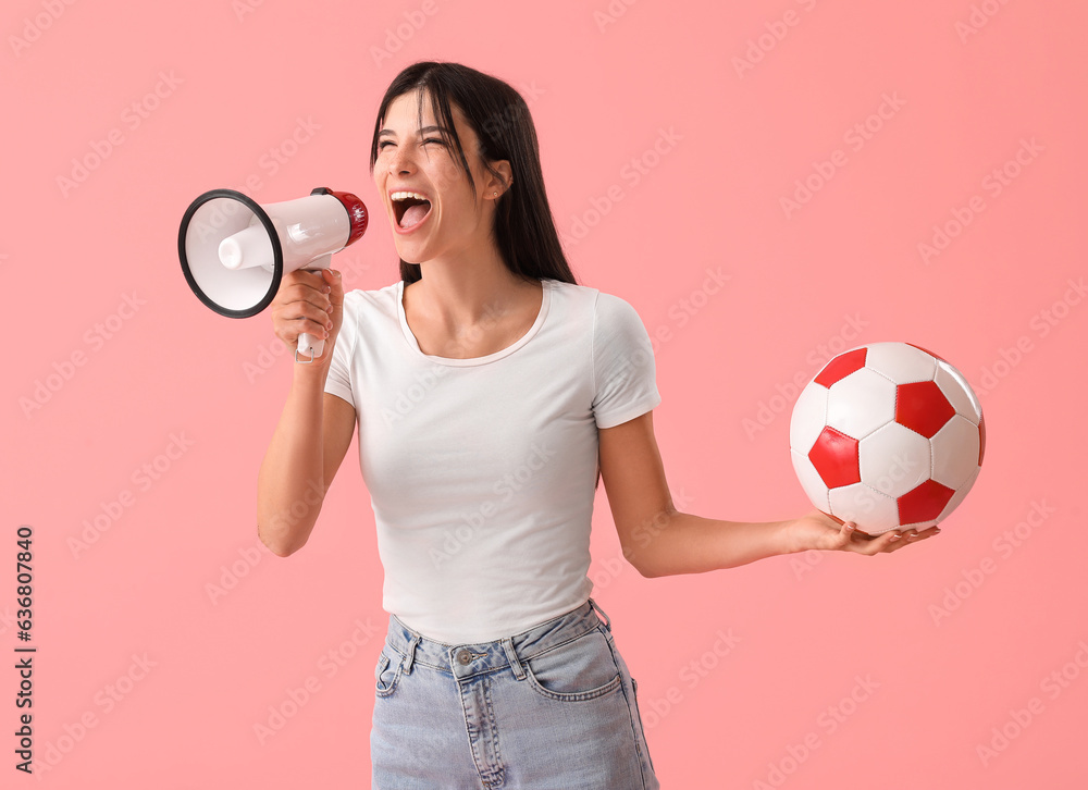 Young woman with soccer ball and megaphone on pink background