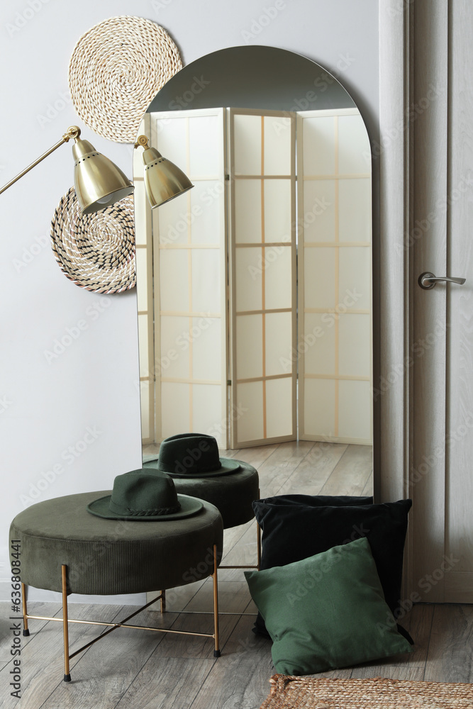 Interior of hallway with mirror, pouf and cushions