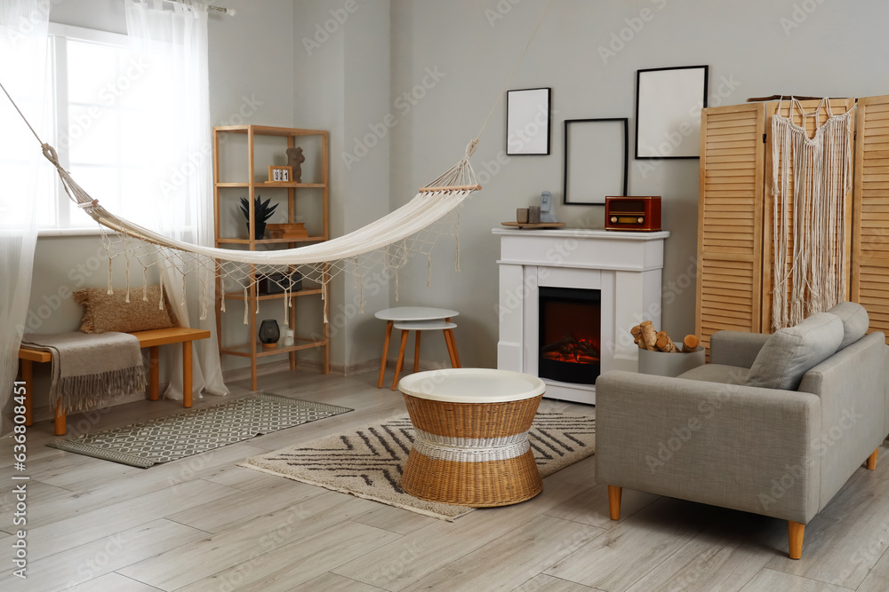 Interior of light living room with fireplace and hammock