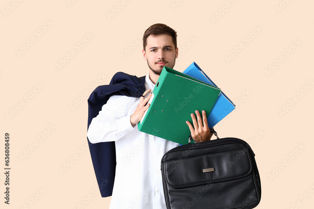 Stressed young businessman with folders on beige background. Deadline concept