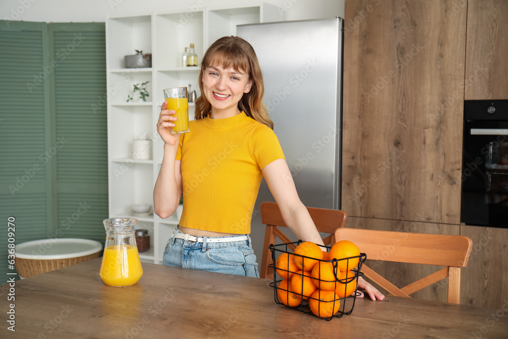 Young woman with glass of orange juice in kitchen