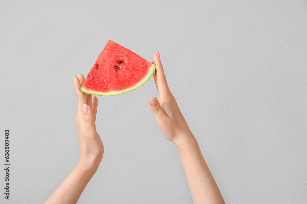 Female hands with piece of ripe watermelon on light grey background