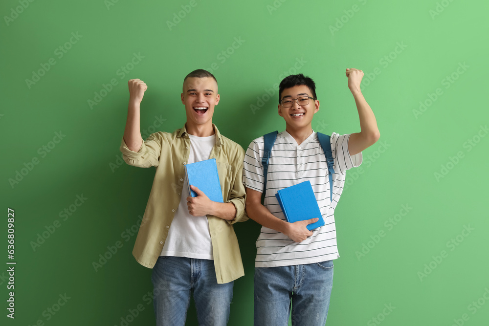 Happy male students with books on green background