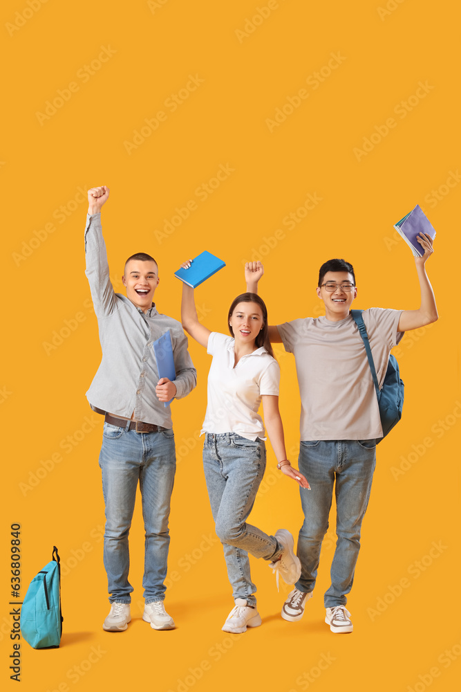 Happy students with backpacks and notebooks on yellow background