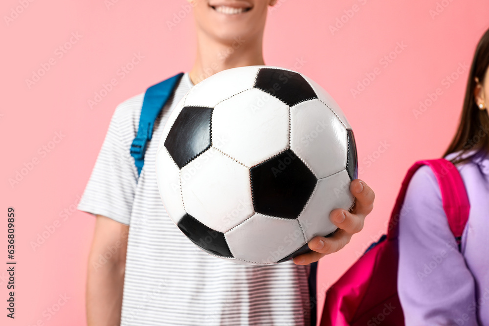 Students with soccer ball on pink background