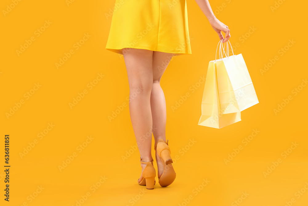 Woman with shopping bags on orange background, back view