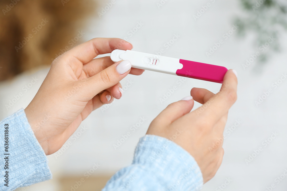 Female hands with positive pregnant test on blurred background, closeup