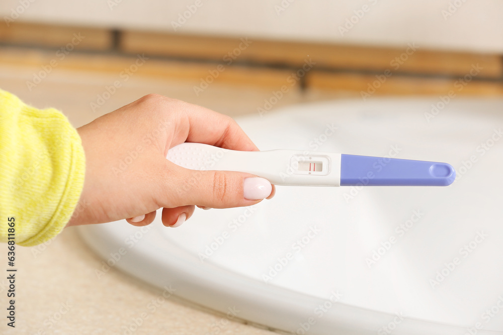 Woman with pregnancy test near sink, closeup