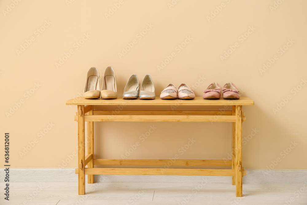 Stylish female shoes on wooden table near color wall