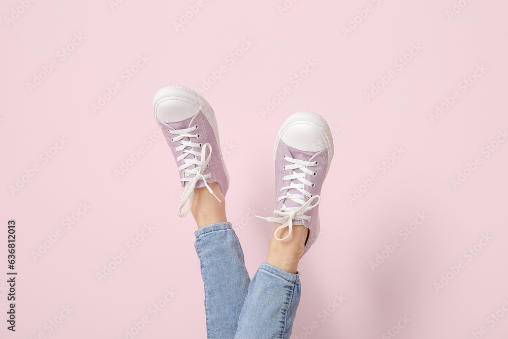 Female legs in stylish gumshoes on pink background