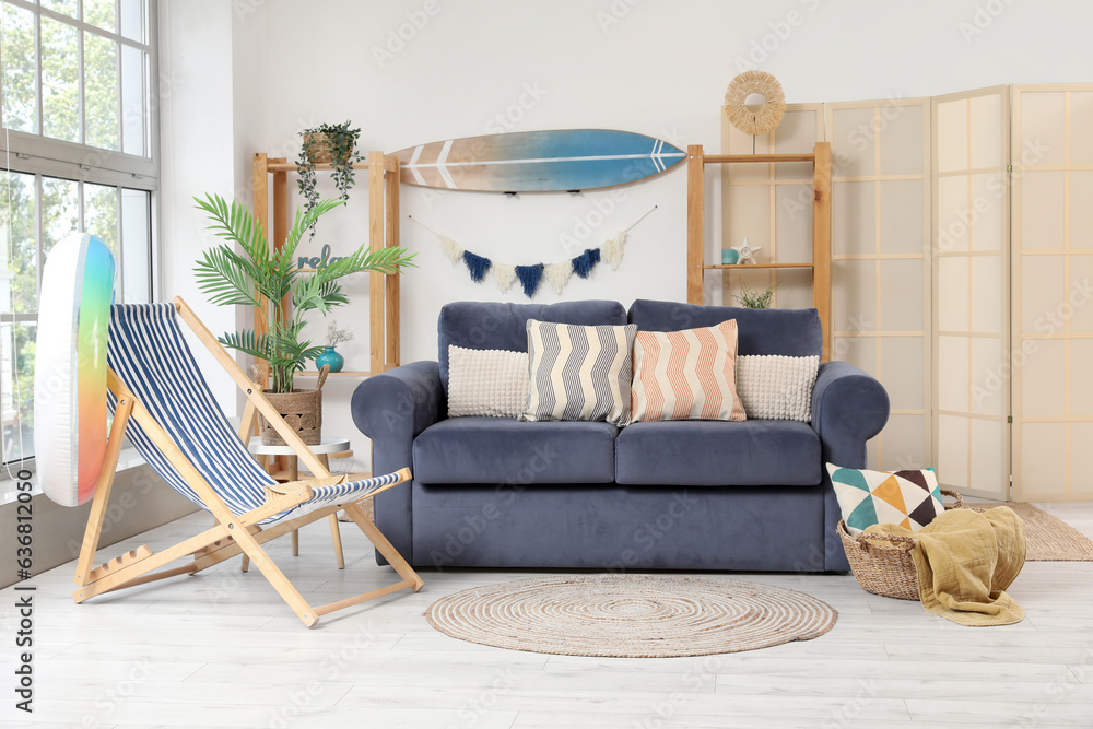 Interior of stylish living room with surfboard and different beach accessories