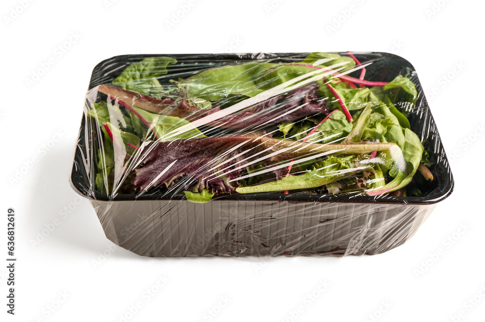 Fresh salad leaves covered with plastic food wrap on white background