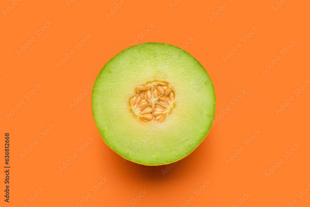 Half of tasty ripe melon on orange background