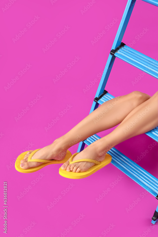 Legs of young woman in flip-flops on magenta background