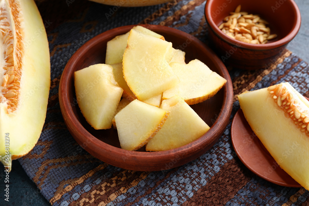 Bowls with pieces of sweet melon and seeds on blue background