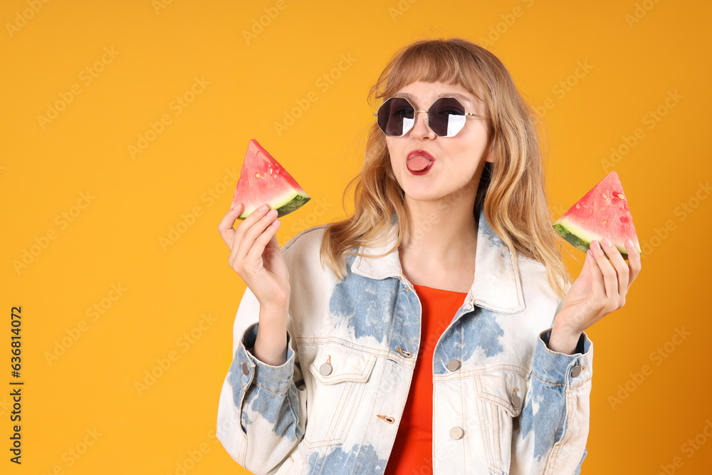 Young woman with slices of fresh watermelon showing tongue on orange background