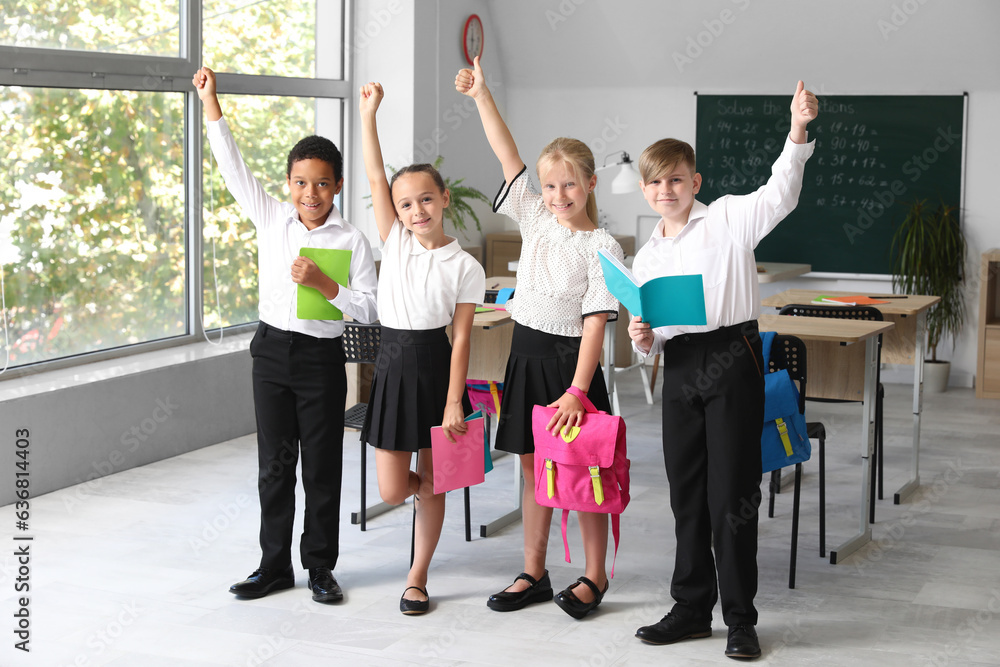 Little classmates with notebooks and backpacks in classroom