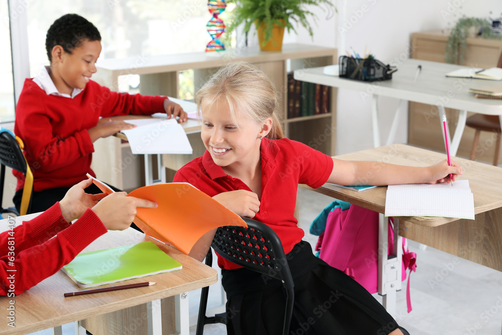 Little classmates sitting at desks during lesson in classroom