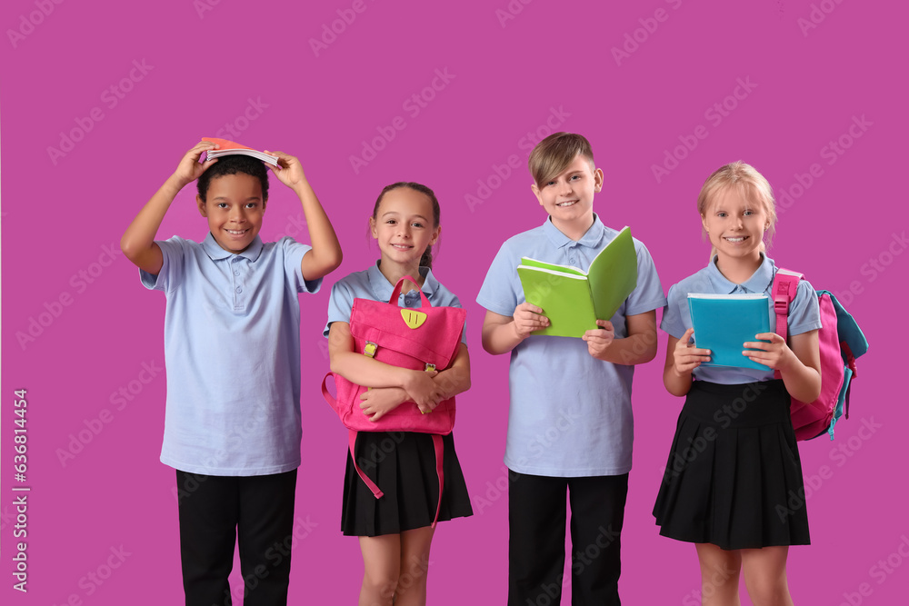 Little classmates in stylish uniform with notebooks and backpacks on purple background