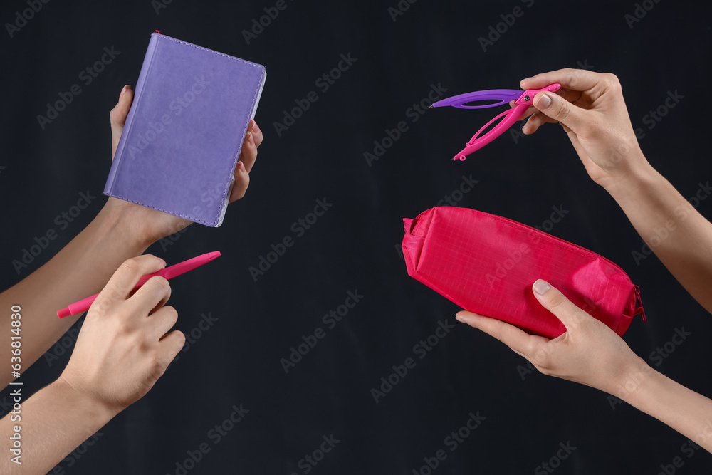 Many female hands with different stationery on black background