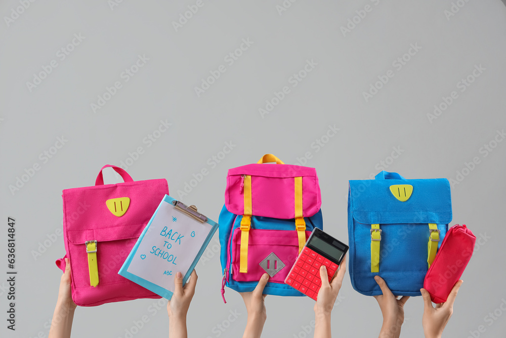 Female hands holding stationery, backpacks and notebook with text BACK TO SCHOOL on grey background