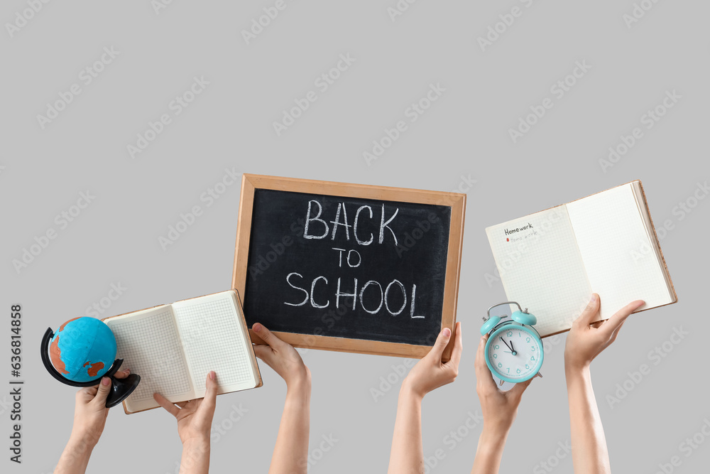 Female hands holding globe, alarm clock and blackboard with text BACK TO SCHOOL on grey background