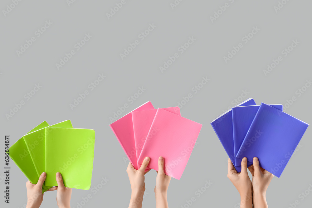 Female hands with many colorful different notebooks on grey background