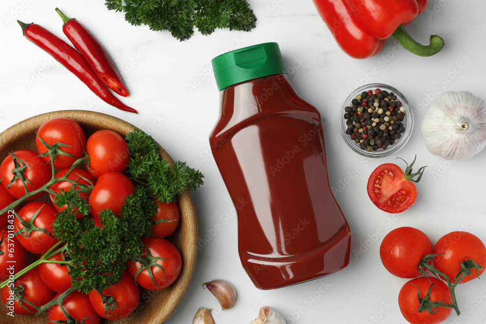 Bottle of tasty ketchup and ingredients on white marble table, flat lay