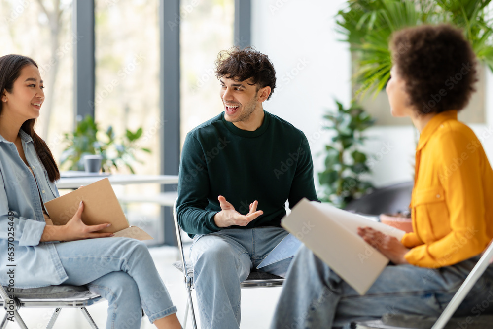 Three diverse enthusiastic friends classmates planning or discussing ideas, communicating in univers