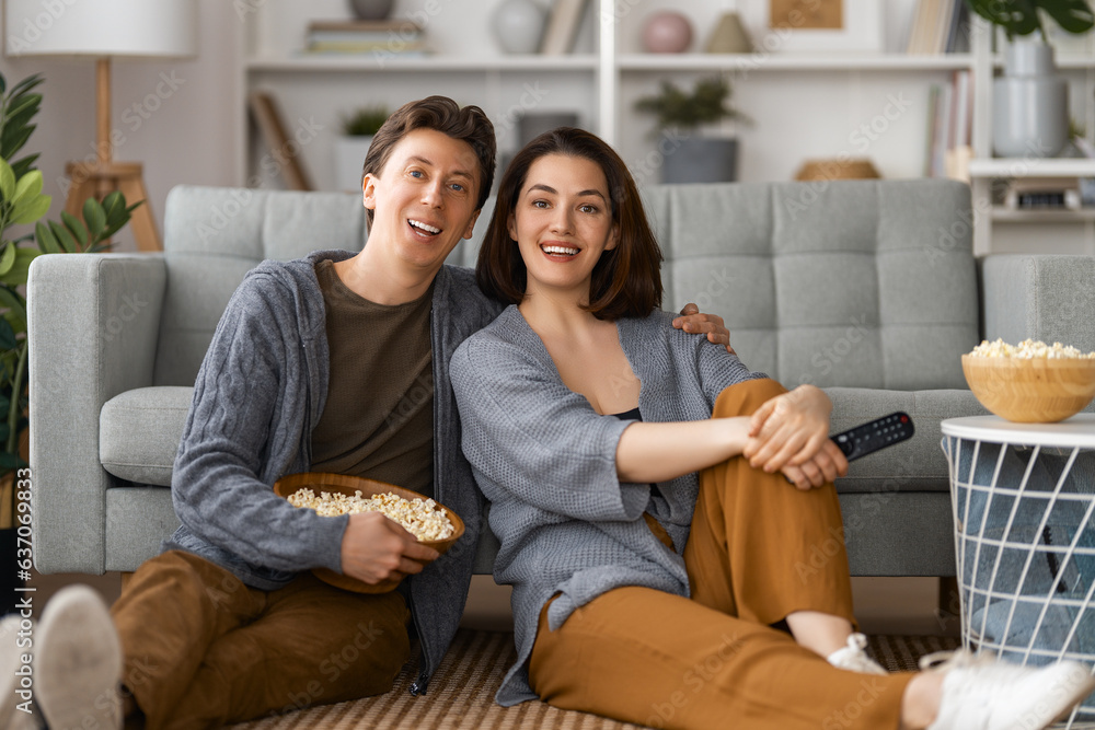 couple with popcorn sitting on sofa