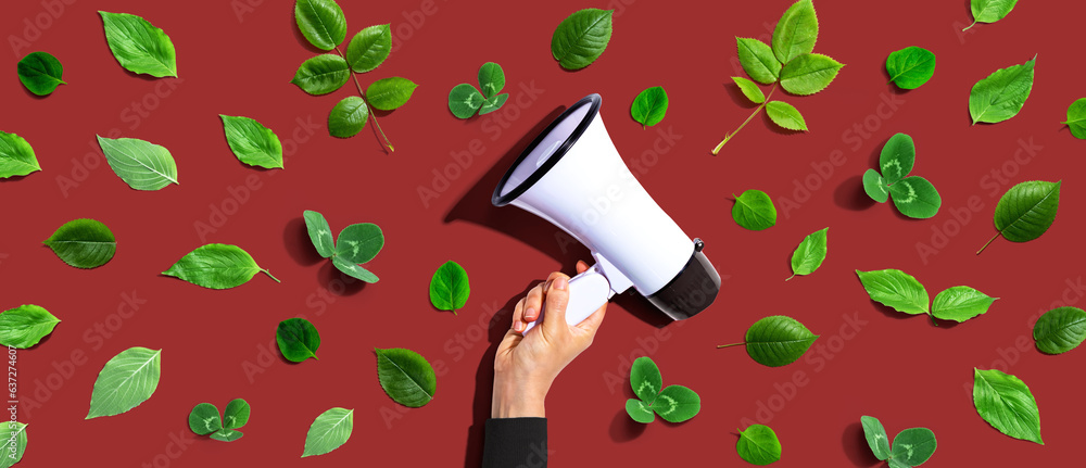 Person holding a megaphone with green leaves - flat lay