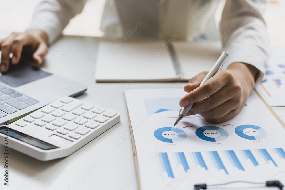 Businesswoman working on documents on laptop in office, business chart analysis in financial reports