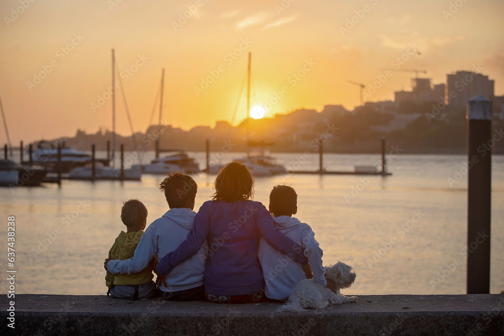 Children, boys, brothers, enjoying sunset over river with their pet maltese dog and mom, boats, sun,