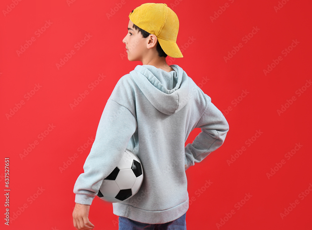 Little boy with soccer ball on red background