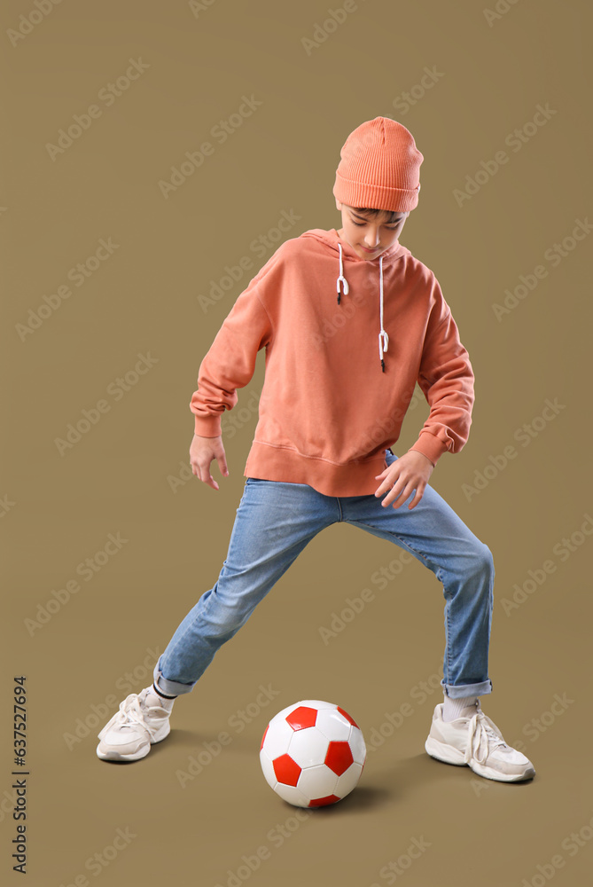 Little boy playing with soccer ball on color background