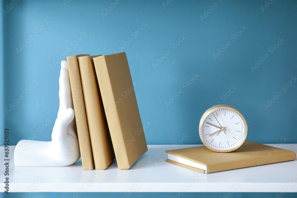 Stylish holder for books on shelf near blue wall