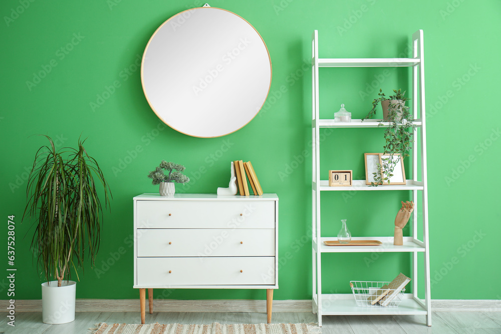 Interior of room with shelving unit and stylish holder for books near green wall