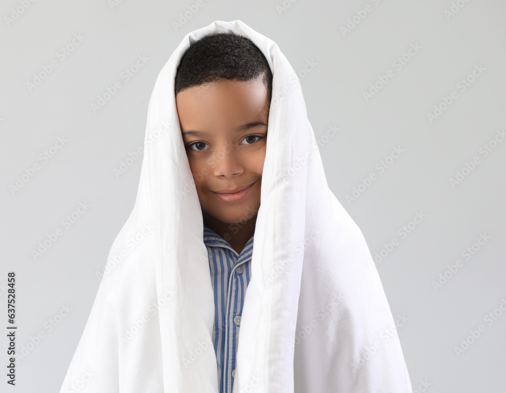 Little African-American boy with soft blanket on light background, closeup