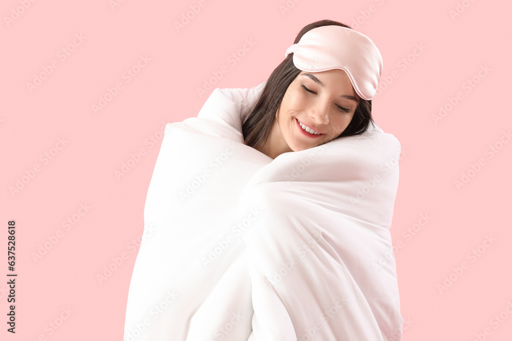 Beautiful happy young woman with soft blanket sleeping on pink background