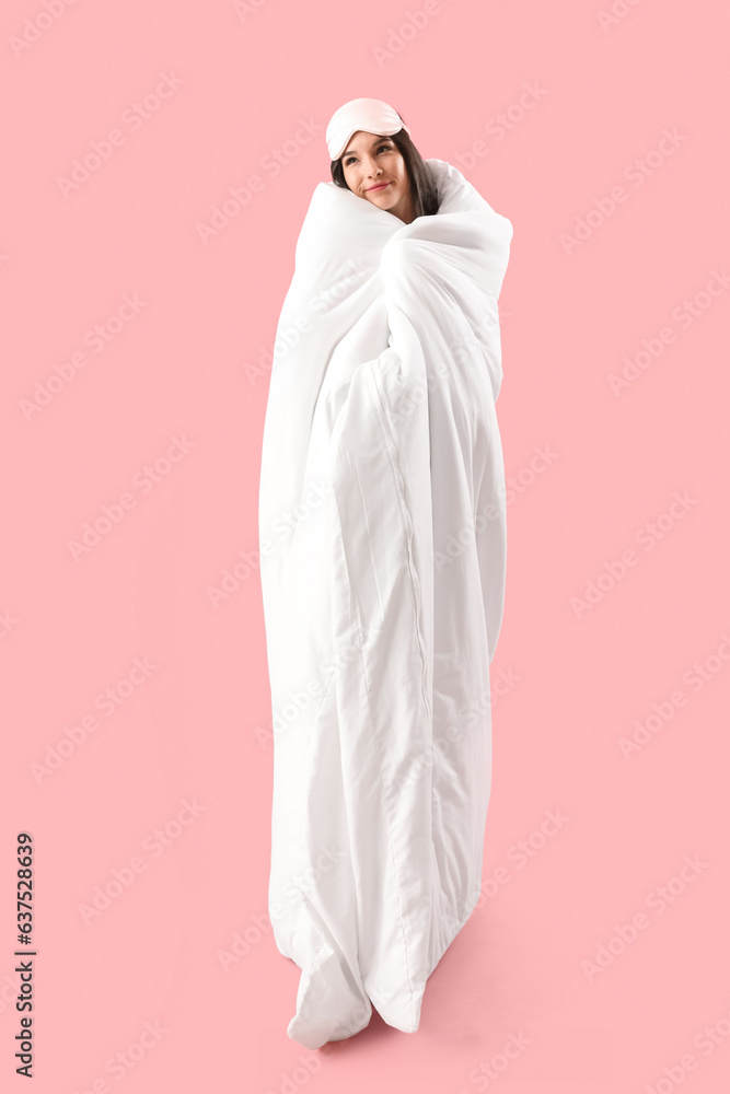 Beautiful dreaming young woman with soft blanket sleeping on pink background