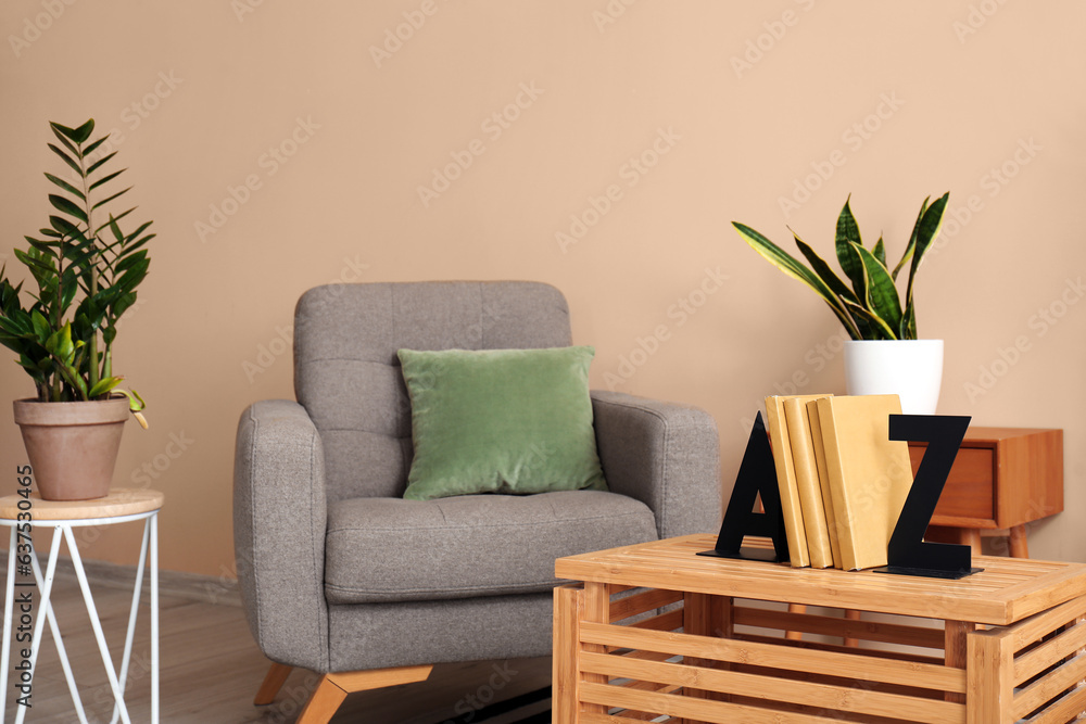 Interior of modern room with armchair and stylish holder for books on wooden table