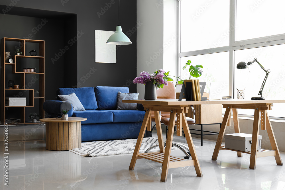 Interior of living room with stylish holder for books and lilac flowers on table