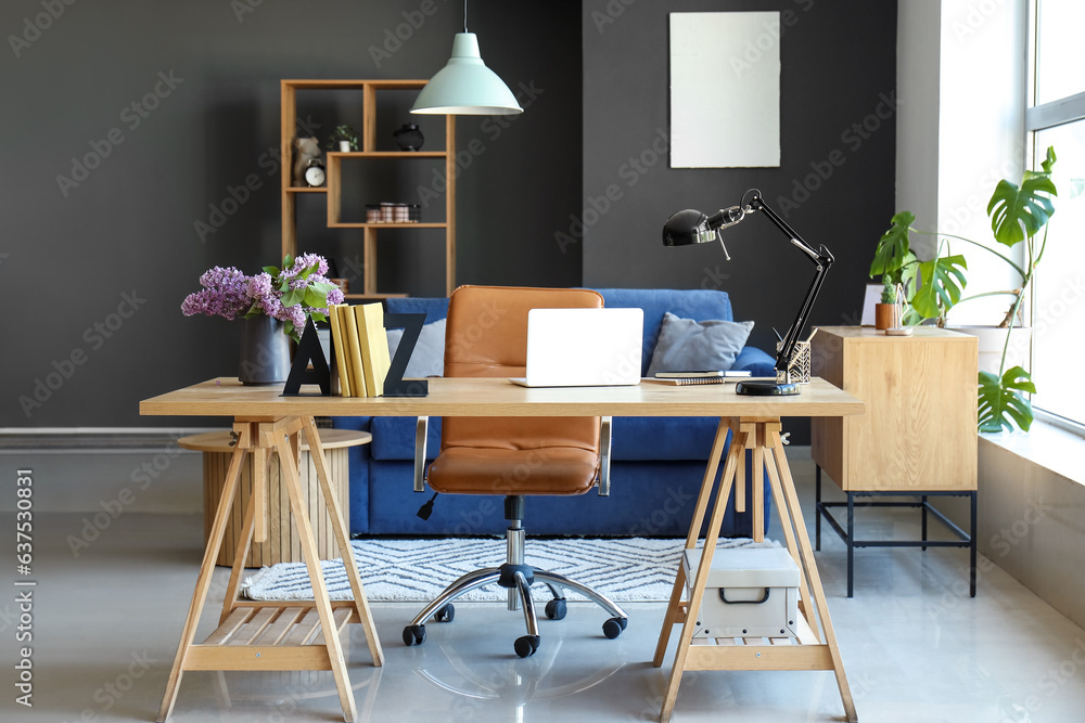 Interior of living room with stylish holder for books and lilac flowers on table