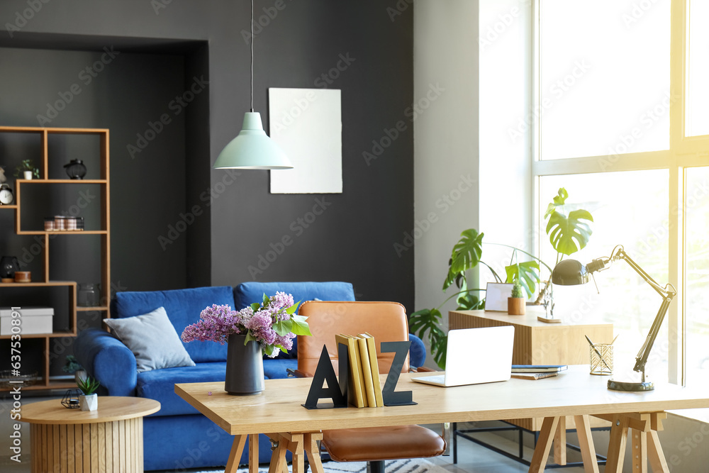 Interior of living room with stylish holder for books and lilac flowers on table