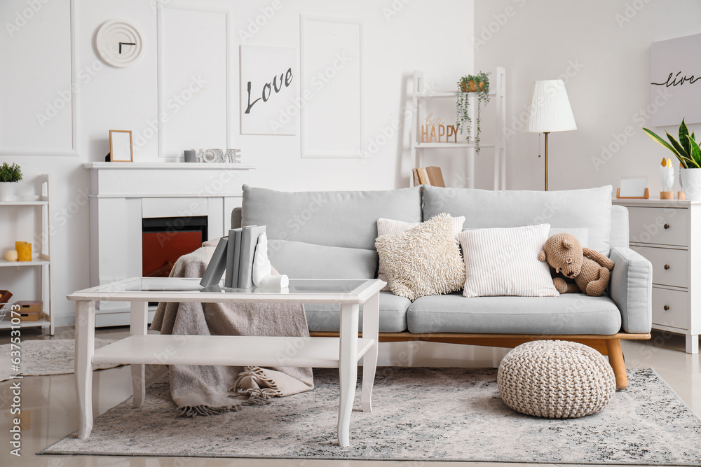 Interior of living room with sofa and stylish holder for books on coffee table