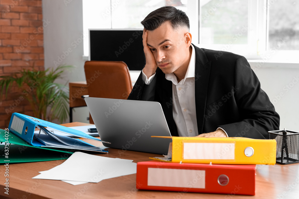 Stressed businessman working under deadline in office