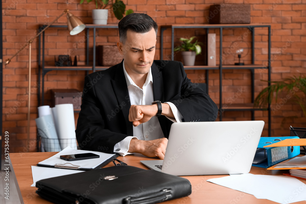 Stressed businessman working under deadline in office