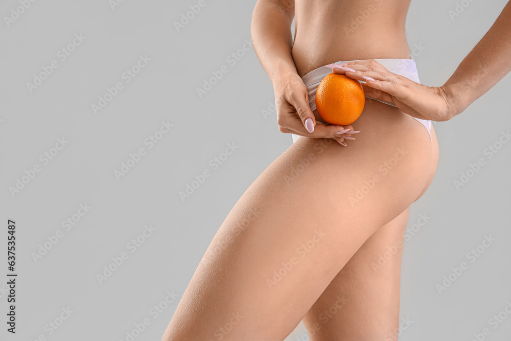 Young woman with cellulite problem and orange on light background, closeup