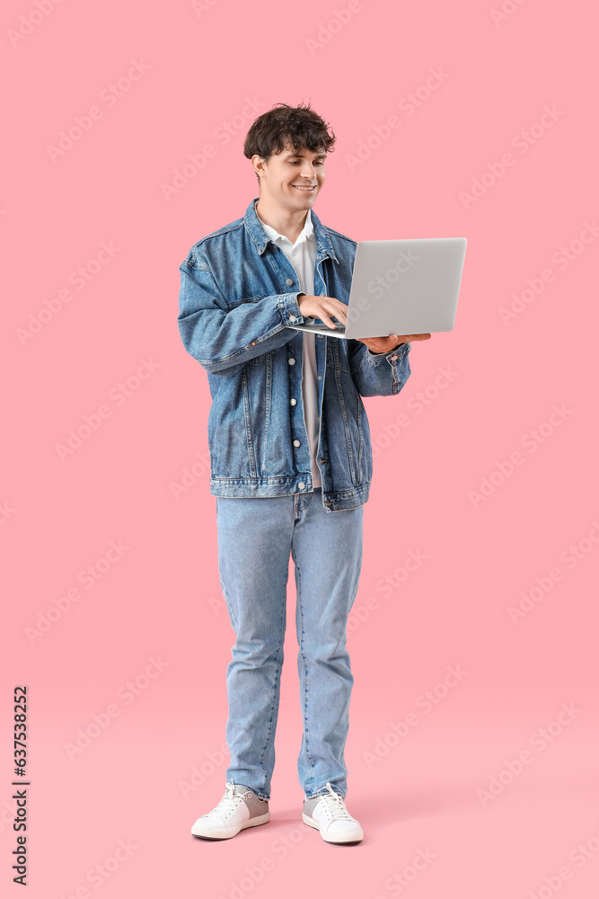 Male programmer working with laptop on pink background