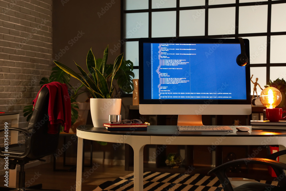 Programmers workplace with computer in dark office